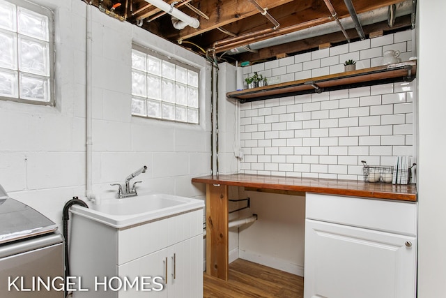 interior space with cabinet space, wood finished floors, concrete block wall, and a sink