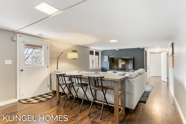 living room with plenty of natural light, baseboards, visible vents, and wood-type flooring