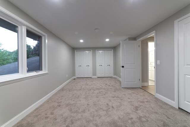 unfurnished bedroom with carpet flooring, recessed lighting, baseboards, and multiple closets