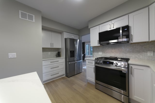 kitchen featuring visible vents, light countertops, light wood-style floors, appliances with stainless steel finishes, and white cabinetry