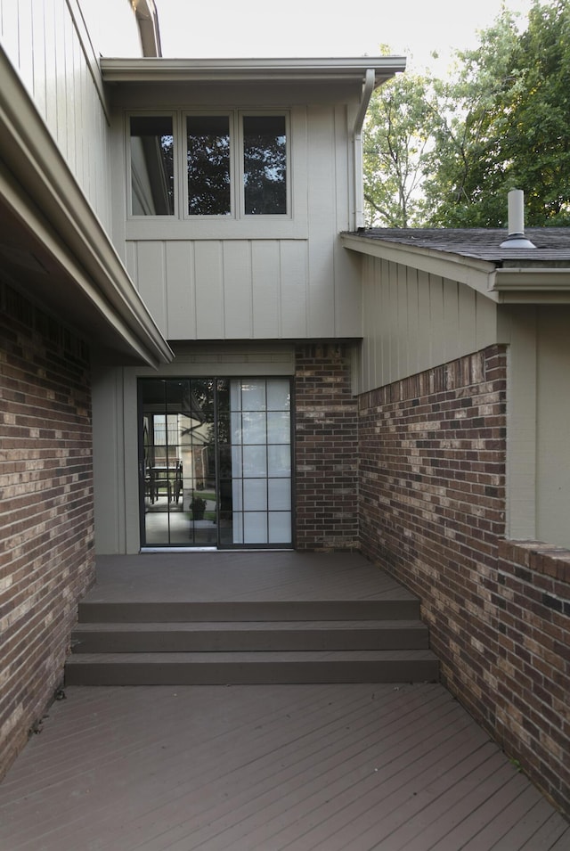 property entrance with brick siding and a wooden deck