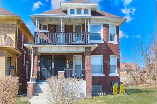 view of front of home with a balcony, brick siding, covered porch, and roof with shingles