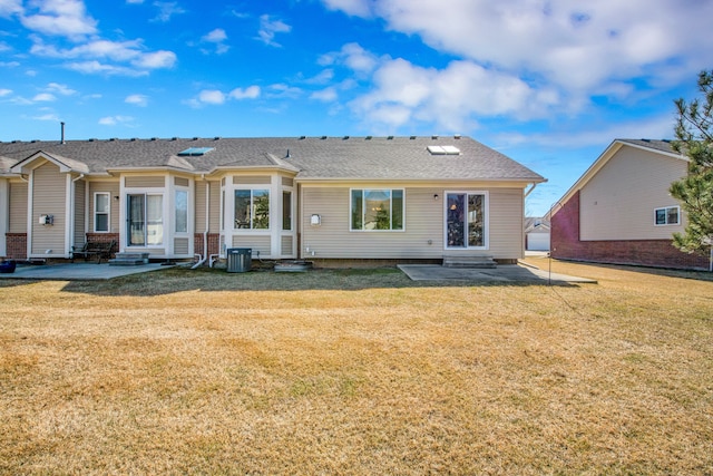 rear view of property featuring entry steps, a patio, a lawn, and central AC