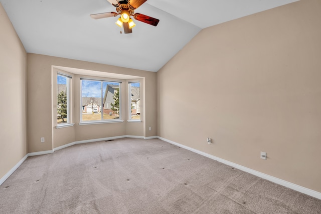 carpeted spare room featuring baseboards, a ceiling fan, and vaulted ceiling