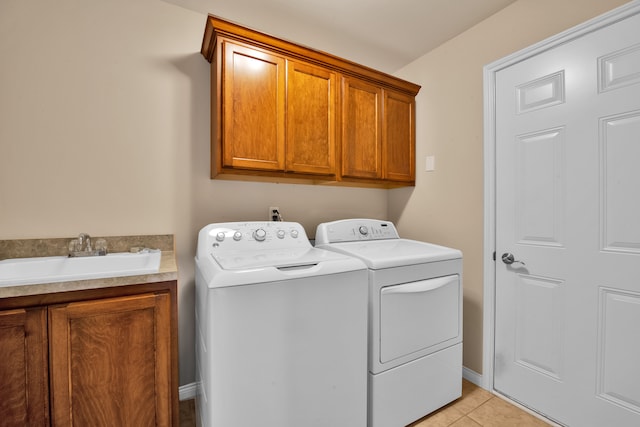 laundry area featuring washing machine and dryer, light tile patterned floors, cabinet space, and a sink