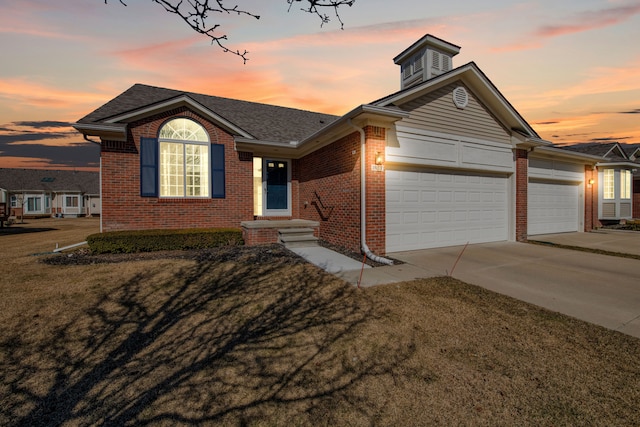 ranch-style home with a garage, brick siding, a yard, and driveway