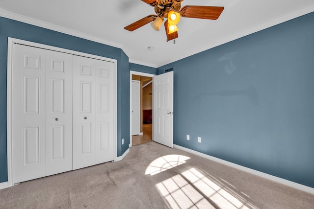 unfurnished bedroom featuring ornamental molding, a closet, carpet, baseboards, and ceiling fan