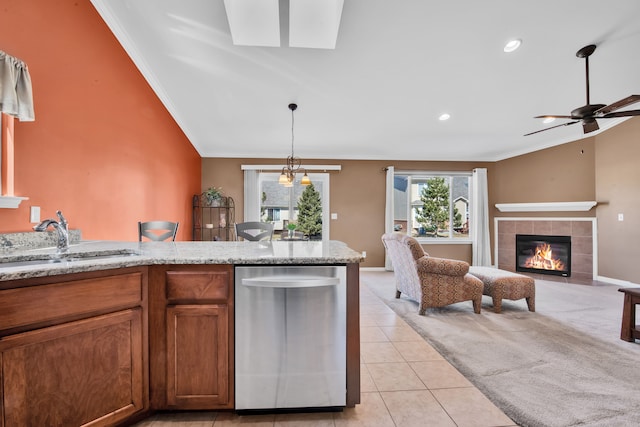 kitchen featuring light tile patterned floors, brown cabinetry, a fireplace, a sink, and crown molding