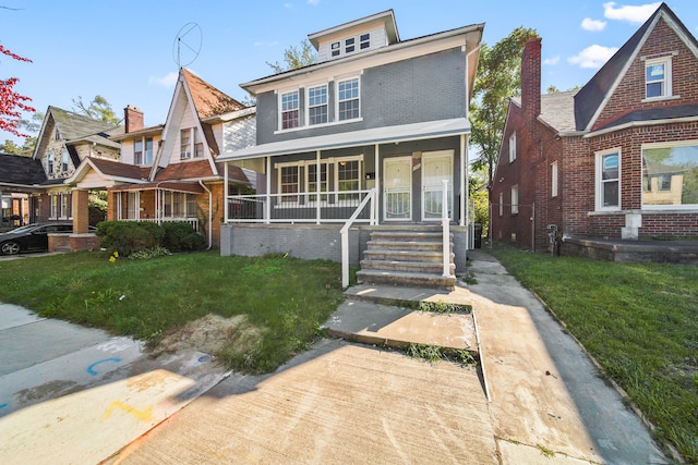 american foursquare style home featuring brick siding, covered porch, and a front lawn