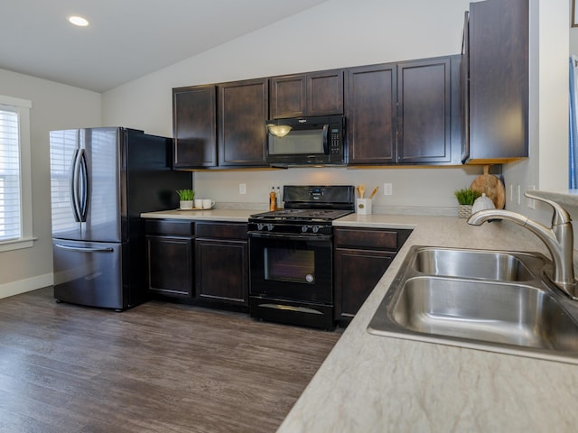 kitchen with lofted ceiling, a sink, black appliances, light countertops, and dark brown cabinets