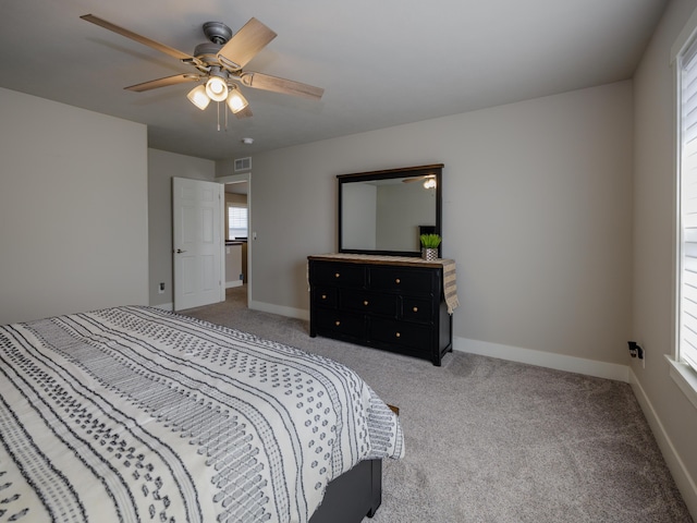 carpeted bedroom with visible vents, baseboards, and ceiling fan