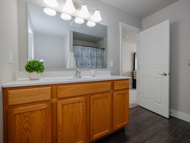 bathroom with vanity, wood finished floors, and baseboards