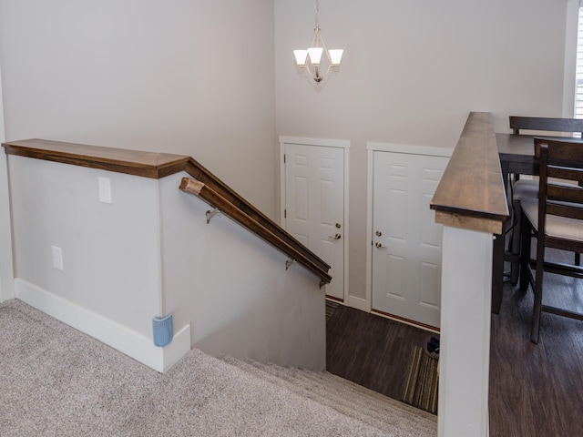 stairs featuring wood finished floors and a chandelier