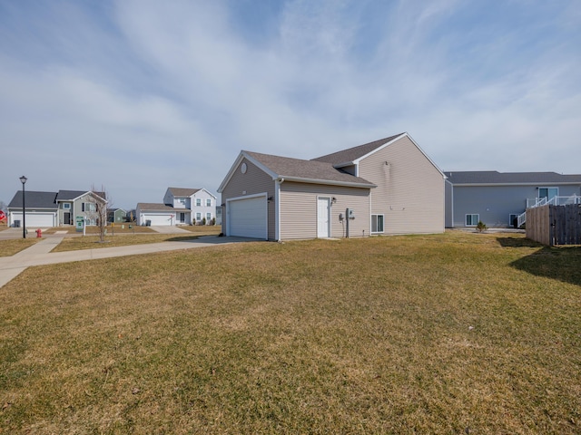 view of side of home with a yard, a residential view, an attached garage, and driveway