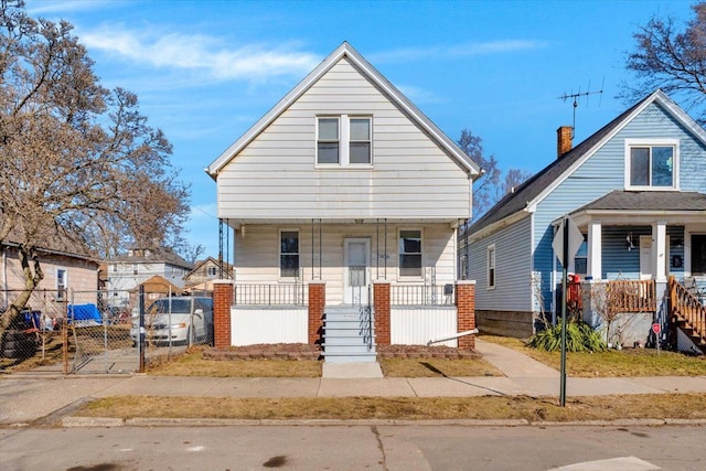 bungalow-style home with covered porch, fence, and a gate