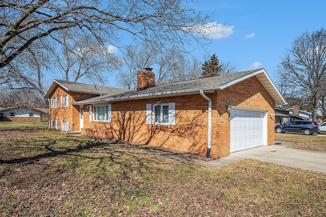 view of side of home with concrete driveway, an attached garage, brick siding, and a chimney