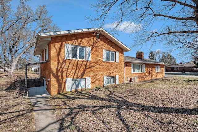 view of property exterior with brick siding and a chimney