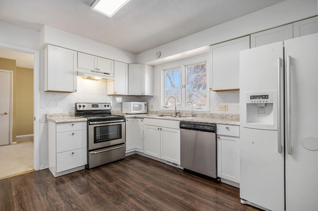 kitchen featuring under cabinet range hood, a sink, stainless steel appliances, white cabinets, and decorative backsplash