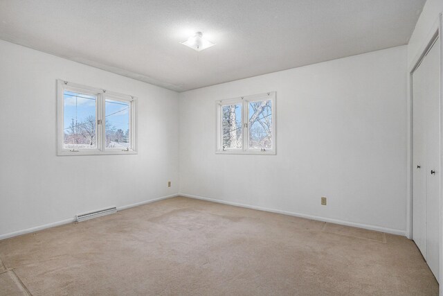 unfurnished room with visible vents, a healthy amount of sunlight, light colored carpet, and baseboards