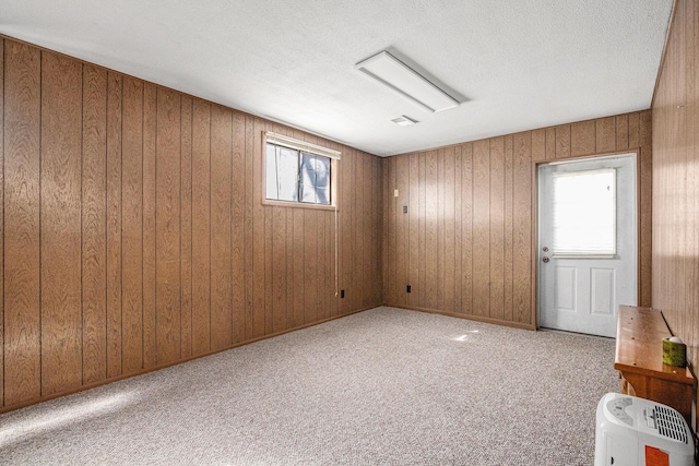 spare room with carpet flooring, wood walls, and a textured ceiling