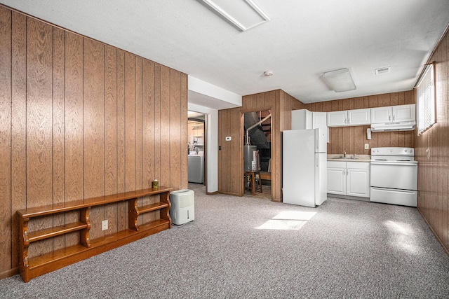 kitchen with a sink, white cabinetry, white appliances, wood walls, and washer / dryer