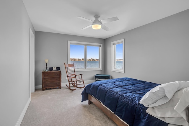 bedroom with baseboards, a water view, carpet, and a ceiling fan