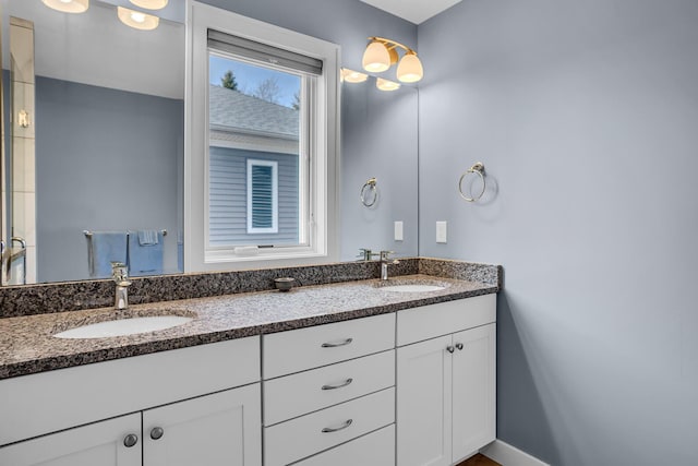 full bathroom featuring a sink, baseboards, and double vanity