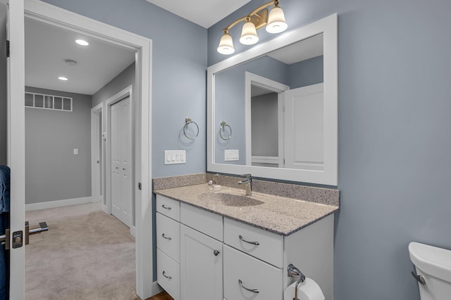 bathroom with vanity, toilet, baseboards, and visible vents