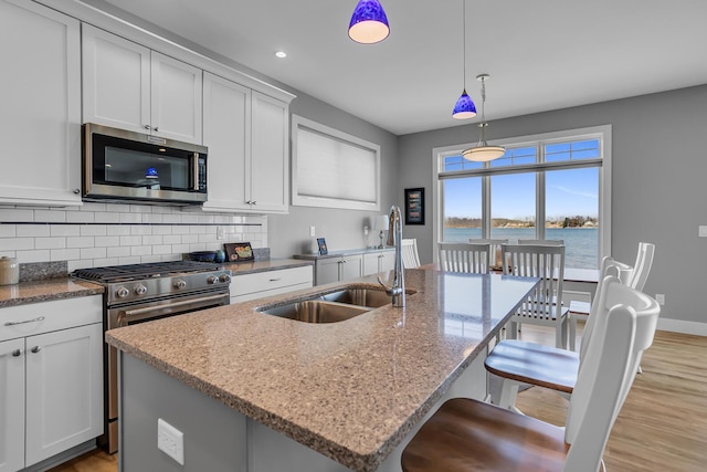 kitchen featuring a sink, decorative backsplash, light stone counters, and stainless steel appliances