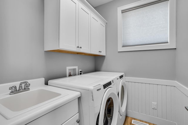 laundry area with a wainscoted wall, visible vents, a sink, cabinet space, and separate washer and dryer