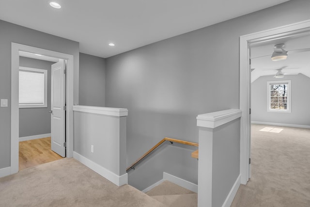 corridor featuring baseboards, an upstairs landing, and carpet floors