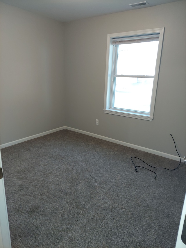 unfurnished room with carpet flooring, visible vents, and baseboards