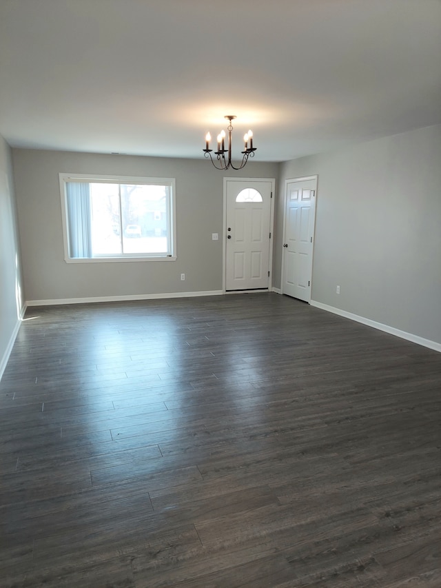 foyer entrance featuring an inviting chandelier, baseboards, and dark wood-type flooring