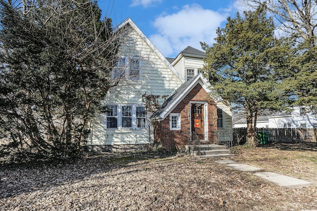 view of front facade featuring fence and brick siding