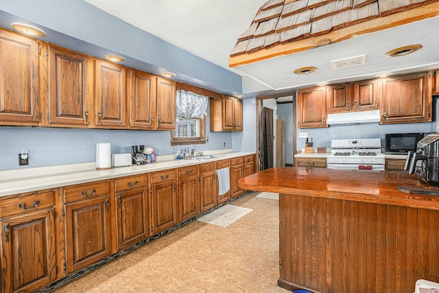 kitchen with light floors, a sink, white gas range oven, under cabinet range hood, and black microwave