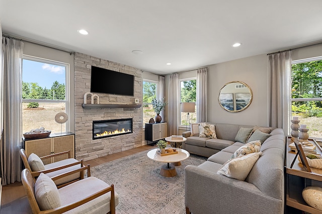 living area featuring a fireplace, recessed lighting, wood finished floors, and a healthy amount of sunlight