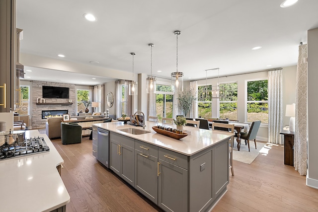 kitchen with gray cabinetry, light wood-style flooring, a sink, a fireplace, and light countertops