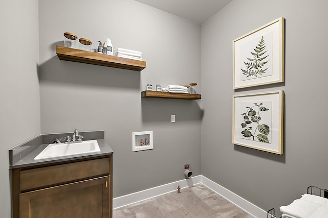 clothes washing area with hookup for a washing machine, baseboards, gas dryer hookup, cabinet space, and a sink