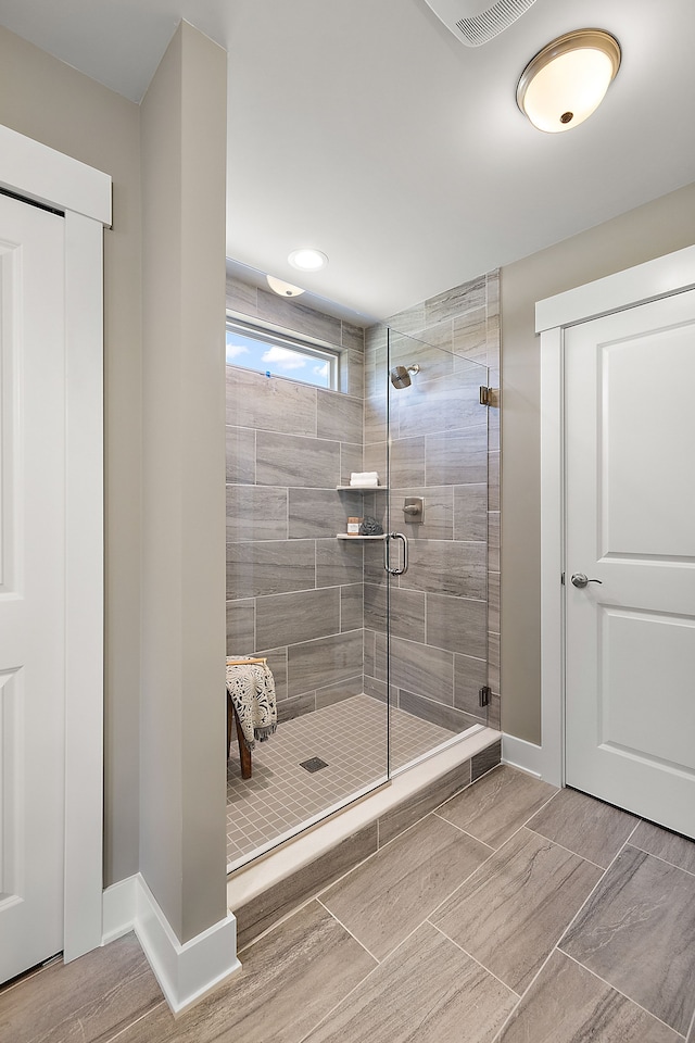 full bath with visible vents, baseboards, wood tiled floor, and a shower stall