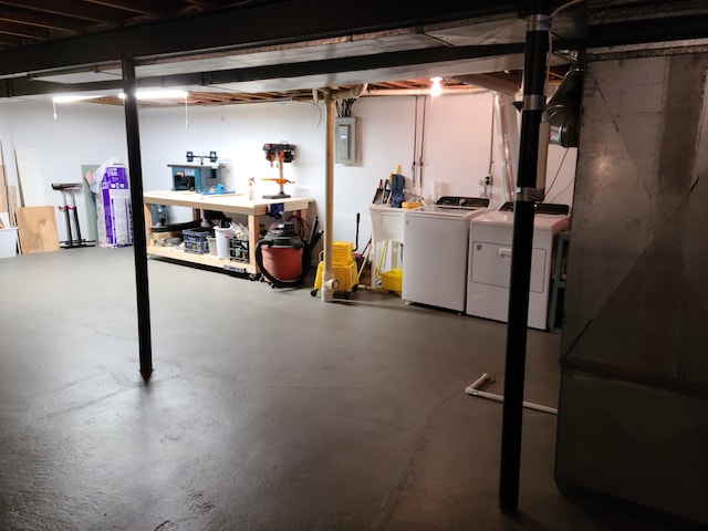 unfinished basement featuring a workshop area, electric panel, separate washer and dryer, and a sink