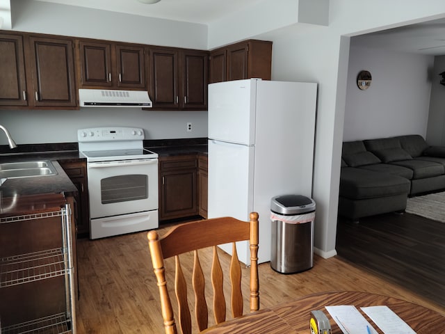 kitchen featuring white appliances, ventilation hood, a sink, dark brown cabinetry, and dark countertops