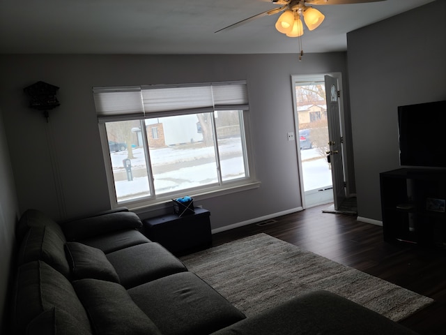 living area with visible vents, baseboards, dark wood-type flooring, and a ceiling fan