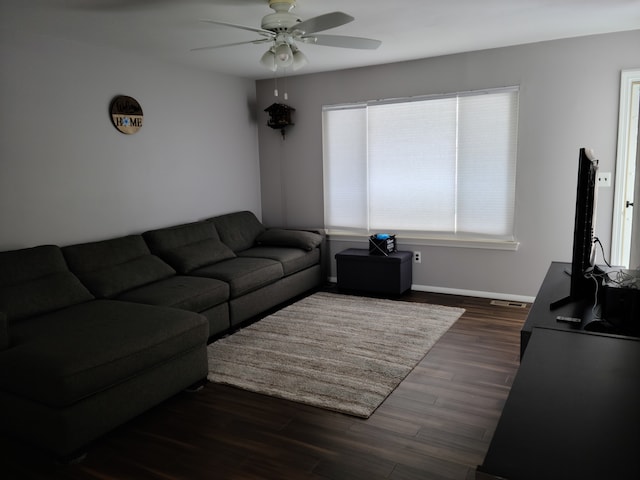 living area with baseboards, dark wood finished floors, and a ceiling fan