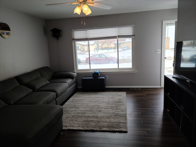 living area featuring dark wood-style floors, a ceiling fan, and baseboards