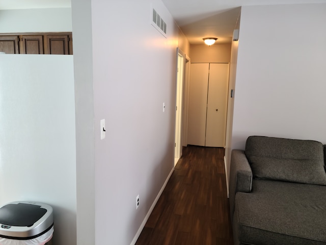 hall featuring visible vents, baseboards, and dark wood finished floors