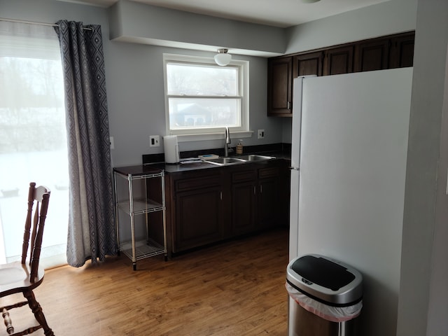 kitchen with dark countertops, light wood-style floors, freestanding refrigerator, and a sink