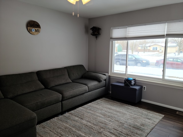 living area with visible vents, a ceiling fan, baseboards, and wood finished floors