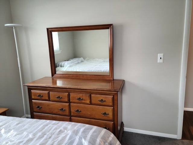 bedroom with baseboards and dark carpet