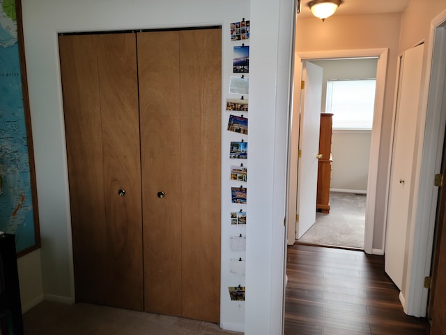 hallway featuring dark wood-type flooring and baseboards