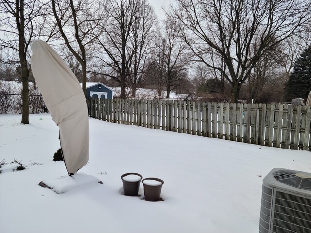 yard covered in snow with cooling unit and fence